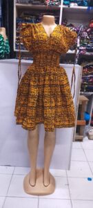 A vibrant African print (Ankara) dress featuring a bold mustard-yellow and black abstract tribal pattern.