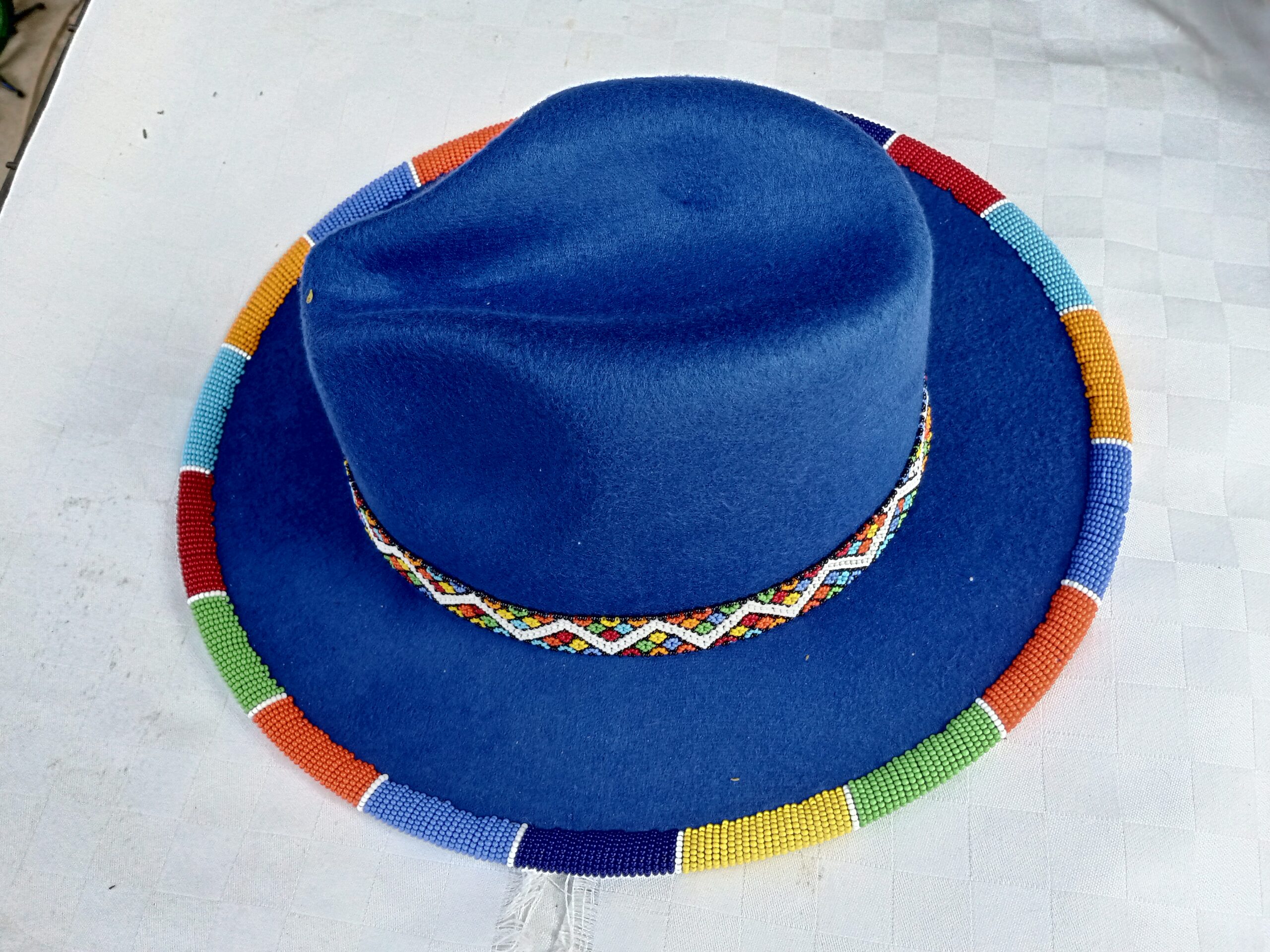Wide-brim felt fedora with a hand-beaded zigzag trim along the brim and crown — a bold, handmade statement hat available in multiple colors.