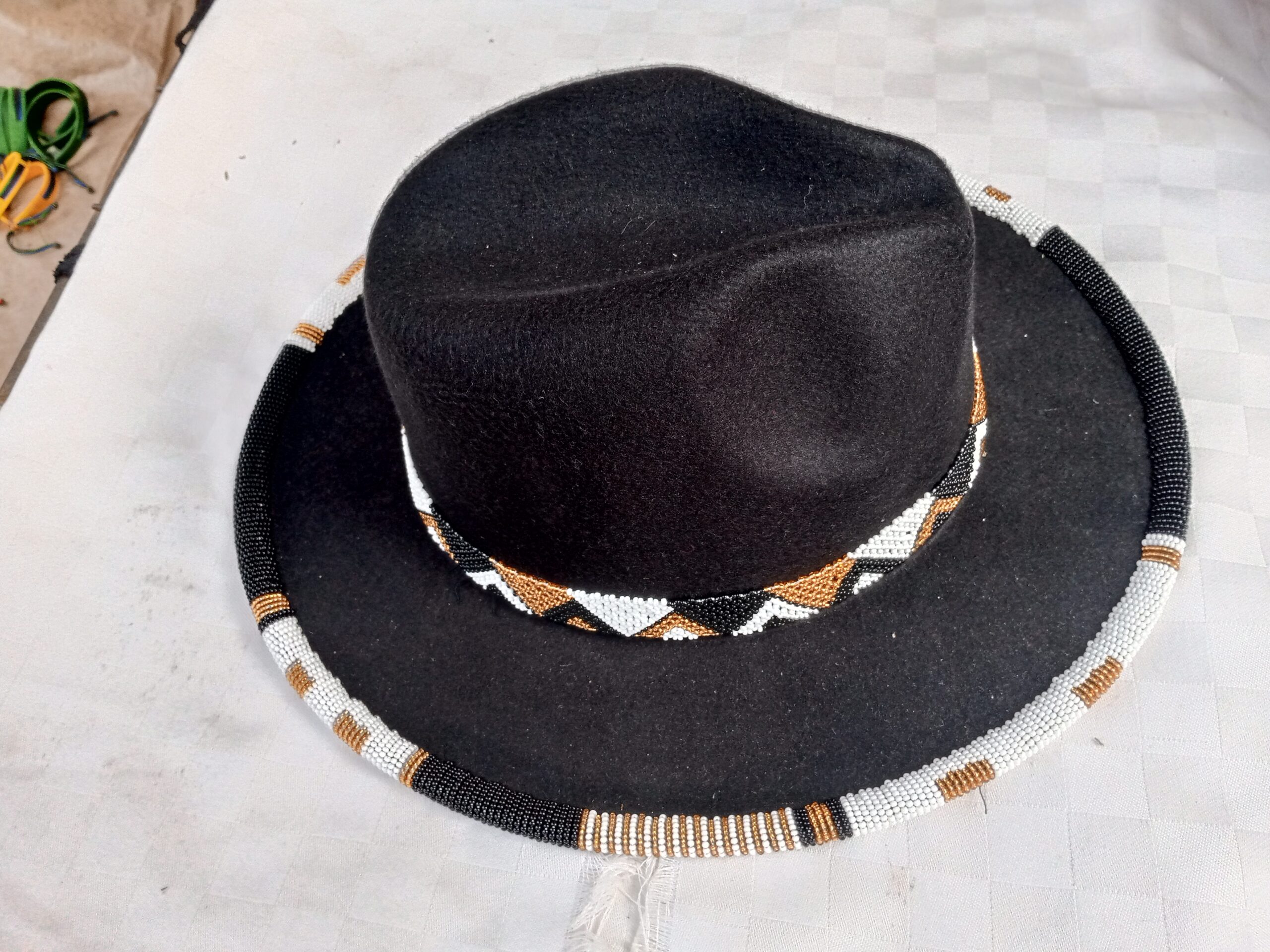 Wide-brim felt fedora with a hand-beaded zigzag trim along the brim and crown — a bold, handmade statement hat available in multiple colors.
