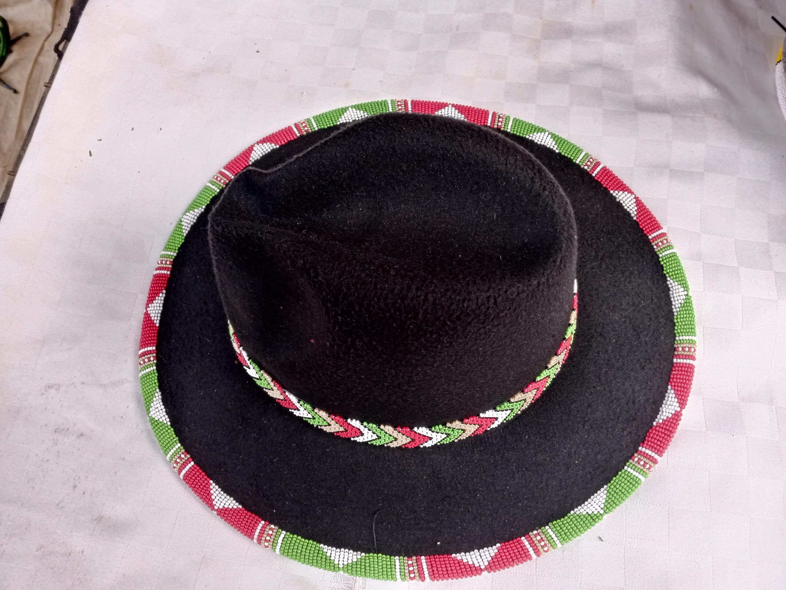 Wide-brim felt fedora with a hand-beaded zigzag trim along the brim and crown — a bold, handmade statement hat available in multiple colors.