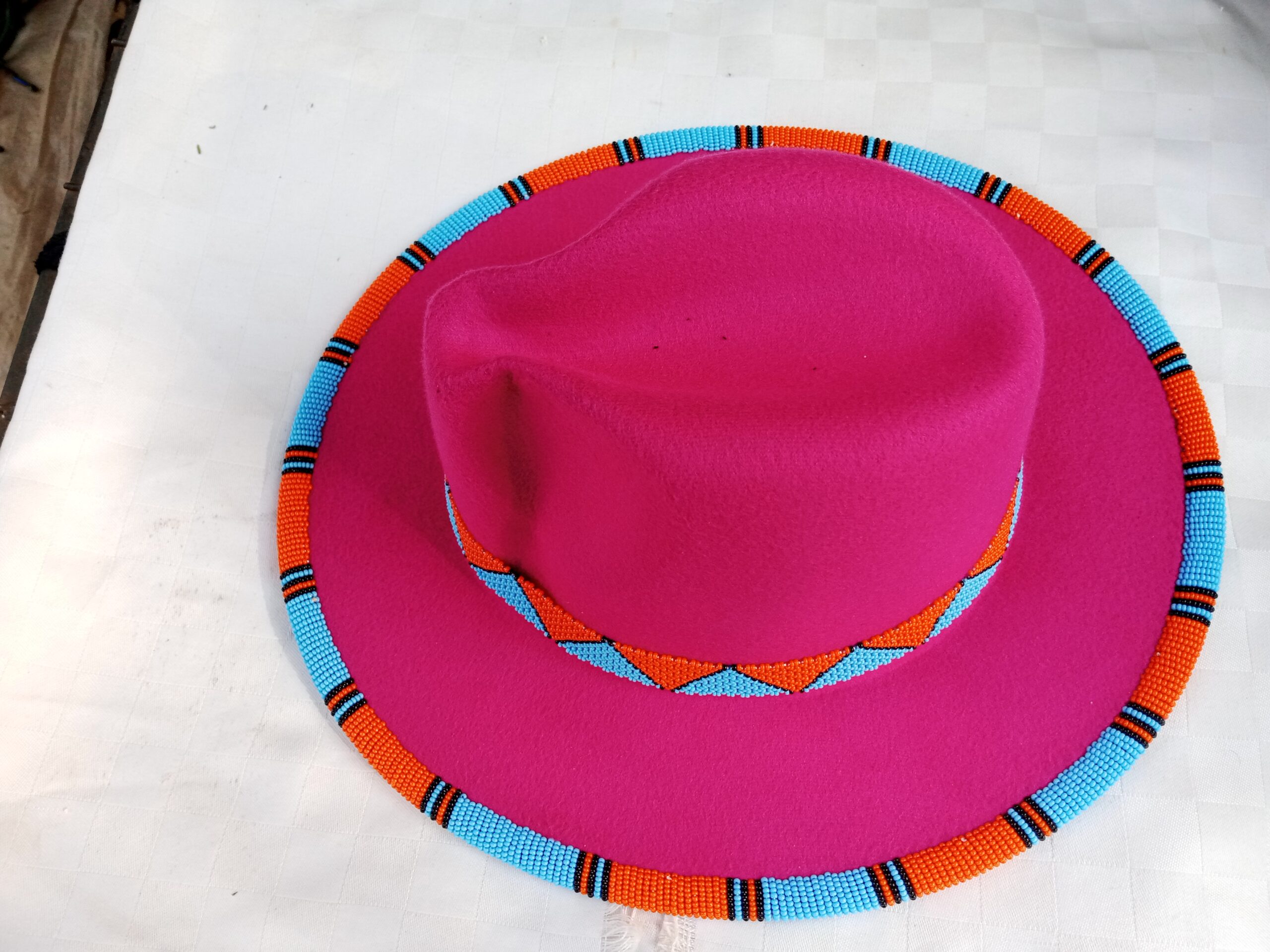 Wide-brim felt fedora with a hand-beaded zigzag trim along the brim and crown — a bold, handmade statement hat available in multiple colors.