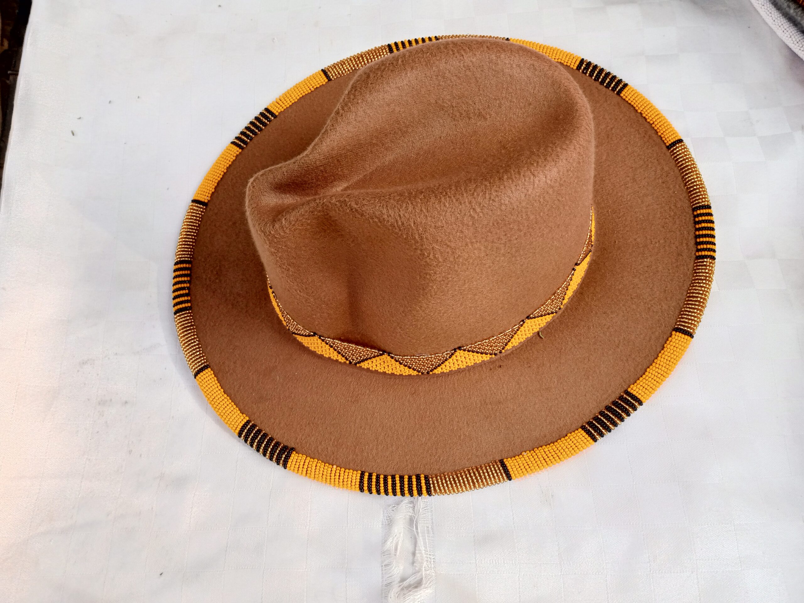 Wide-brim felt fedora with a hand-beaded zigzag trim along the brim and crown — a bold, handmade statement hat available in multiple colors.