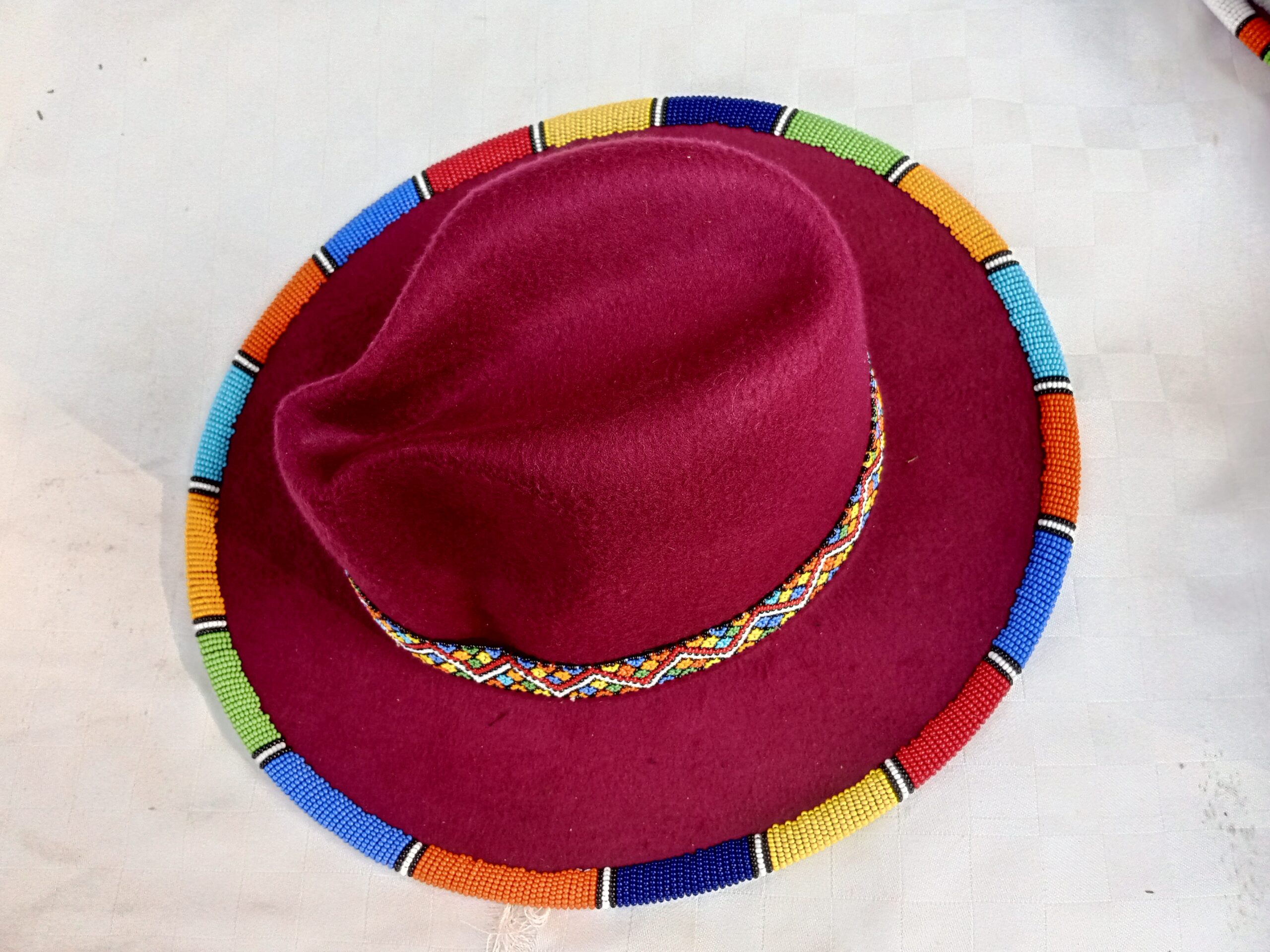 Wide-brim felt fedora with a hand-beaded zigzag trim along the brim and crown — a bold, handmade statement hat available in multiple colors.