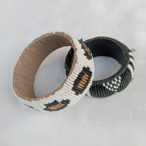 Handmade Maasai beaded leather bangles with a bold zigzag pattern in white, black, and gold/silver tones. Sturdy, statement-making tribal jewelry crafted with authentic beadwork detail.
